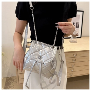 Silver quilted mini backpack with metallic finish and chain strap worn by a model