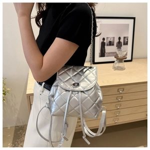 Close-up of silver quilted mini backpack with metallic finish and chain strap on a model