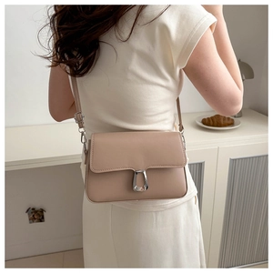 Detailed view of apricot leather crossbody bag with silver U-shaped metal buckle on model