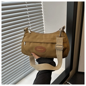 Detail of coffee brown canvas bag with round Fashion leather patch and thick woven strap