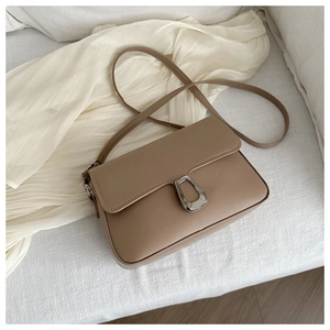 Detail of khaki leather crossbody bag with silver metal lock on white fabric