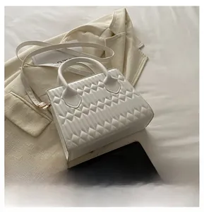 Detail of white quilted leather texture on a stylish minimalist crossbody square bag