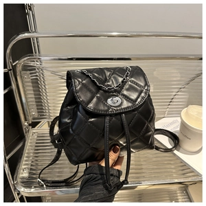 Detail of black quilted PU backpack featuring silver turn-lock and chain handle on display