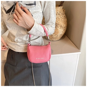 Detail of pink lychee leather handbag with silver bead chain and elegant top handle