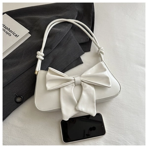 Close-up of white faux leather shoulder bag with a large sweet bow and knot detail