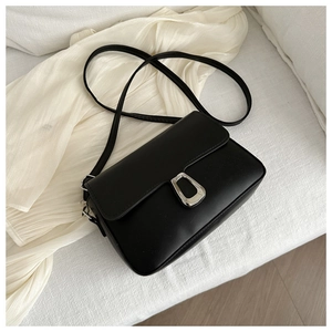 Close-up of black leather crossbody bag with elegant silver U-shaped metal buckle
