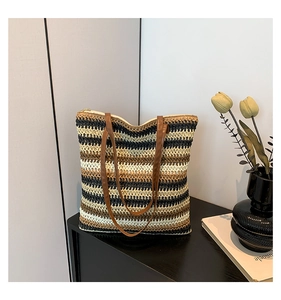 Detail of colorful striped straw tote bag with brown leather straps on a modern side table