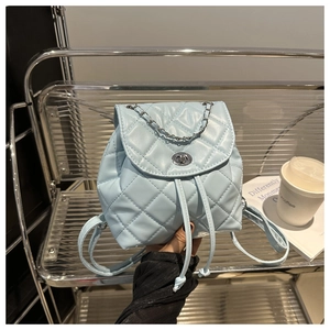 Detail view of light blue quilted leather backpack with silver chain and metal twist lock