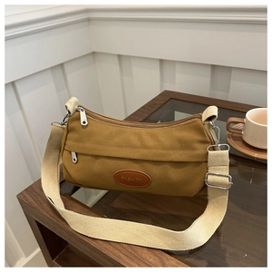 Close-up of yellow canvas shoulder bag with fashion leather patch and silver metal zippers