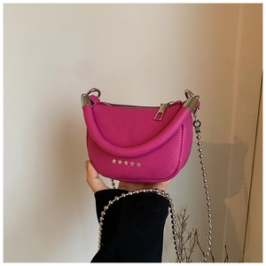 Detail of pink crescent bag with lychee leather and gold star studs held by hand