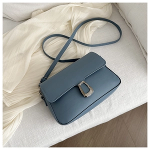 Close-up of Morandi blue leather handbag featuring a D-shaped metal buckle and flip cover