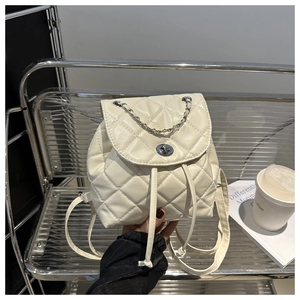 Detail of cream quilted mini backpack featuring silver twist lock and chain strap