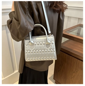Silver quilted small square bag with textured embroidery shown on model for shoulder style