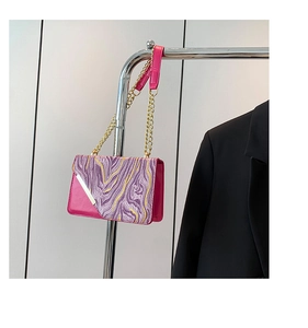 Dettaglio borsa in pelle fucsia con patta marmorizzata e tracolla a catena oro su gruccia