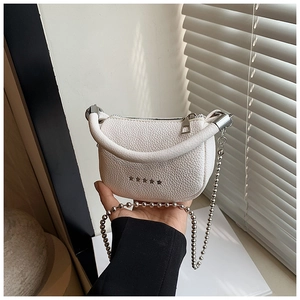 Close-up of white lychee pattern leather handbag with silver star studs and chain strap