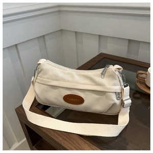 Detail of off-white canvas shoulder bag with brown FASHION patch and wide strap