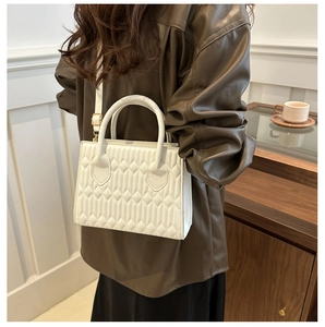 White quilted rectangular bag shown on model with dual handles and long strap