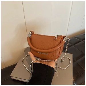 Detail view of brown lychee leather bag featuring silver star studs and beaded chain