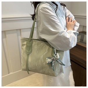 Model wearing a light green pleated tote bag featuring a decorative fashion print scarf