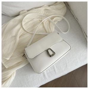 Detail of white minimalist flap bag with silver metal buckle on a soft fabric texture