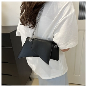 Detail of black geometric shoulder bag with unique pointed edges and silver chain strap