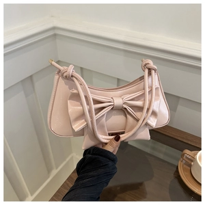 Detail of a pink bow shoulder bag made of glossy patent leather with knotted handle