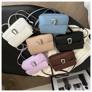 Flat lay of minimalist square crossbody bags in six assorted colors with metal U-buckle