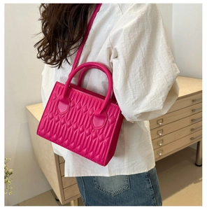 Detailed view of magenta quilted crossbody bag worn by model to show size and texture