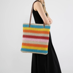Colorful striped straw tote bag for women with brown leather straps shown on shoulder