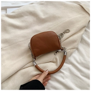 Close-up of brown litchi pattern leather bag with silver chain and circular handle