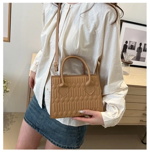 Detail of camel leather handbag with geometric embossed texture and round top handle