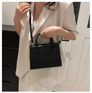 Detail of black geometric quilted crossbody bag with gold hardware and top handle