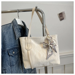 Detail of white textured tote bag with a fashion printed silk scarf on a metal stand