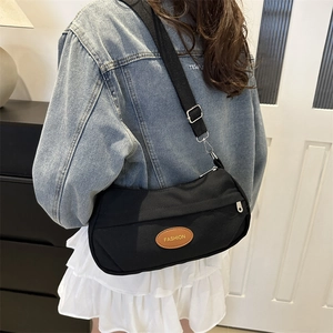 Fashionable black canvas crossbody bag for women with adjustable strap and leather logo tag
