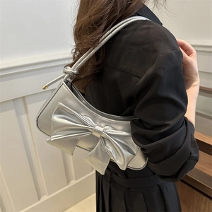 Silver metallic shoulder bag with large bow and knot detail worn on shoulder