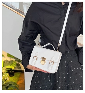 Detail of white minimalist crossbody bag with gold buckle and adjustable strap