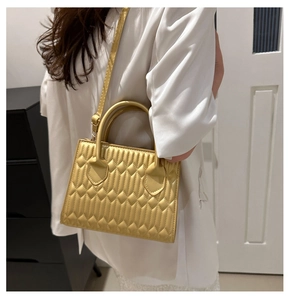 Detail of ginger yellow quilted handbag featuring fine diamond stitching and top handle