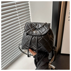 Detail of black quilted leather backpack with silver chain and twist lock closure