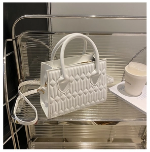 Detail of white quilted faux leather handbag with circular handles and gold hardware