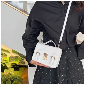 Side view of woman carrying a white retro crossbody bag with gold lock and top handle