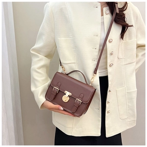 Brown vintage faux leather crossbody bag with golden buckle shown on a chic tweed blazer