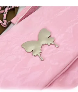 Detail of pink glossy textured shoulder bag featuring large silver metal butterfly clasp