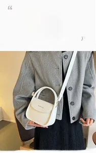 Détail d'un petit sac à bandoulière blanc minimaliste porté sur un manteau en laine