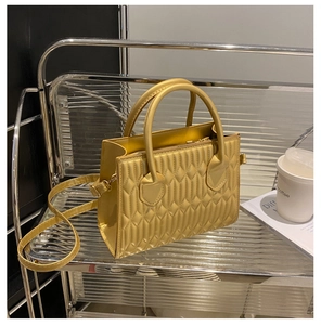 Detail of yellow quilted leather crossbody bag with rhombic stitching and double handles