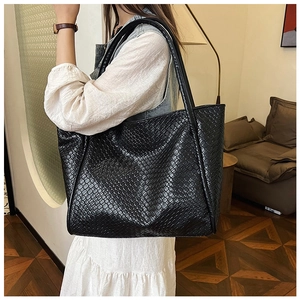 Close-up of black woven leather tote bag texture and design on a model's shoulder