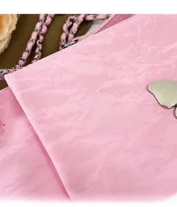 Detail of pink shoulder bag with pleated texture and silver butterfly metal buckle
