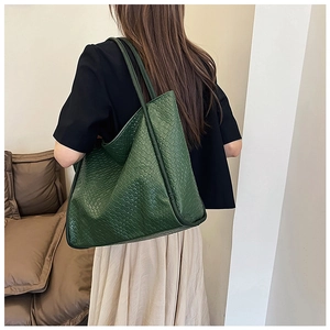 Macro shot of dark green woven tote bag showing luxury leather texture and handle details