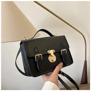 Macro shot of retro black square bag with premium PU texture and gold metal buckle detail