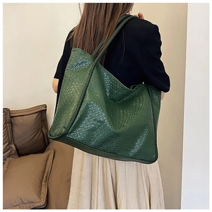Detail of green woven tote bag showing the textured large capacity shoulder bag on a model