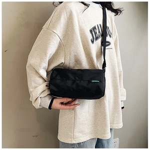 Detail of black nylon rectangular crossbody bag with green label and wide strap
